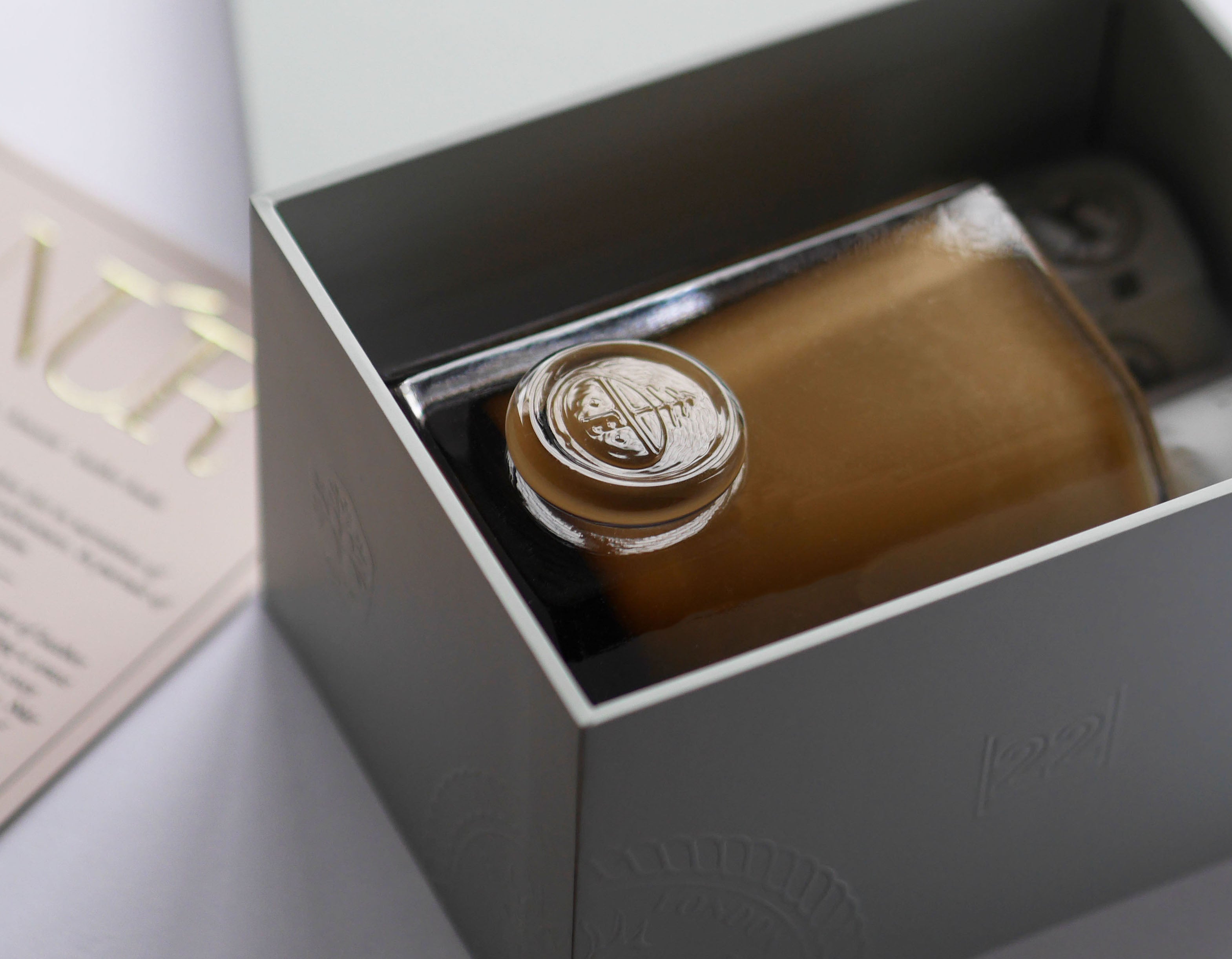 An ENYALYË vessel candle presented in its gift box, with the glass vessel's engraved emblem visible inside.